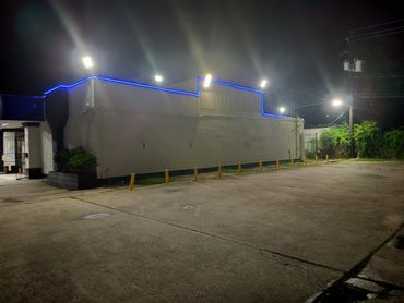 Empty parking lot beside a building with blue neon lights at night.