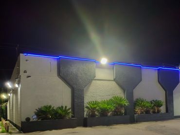 Night view of a building with blue strip lighting and parked car.