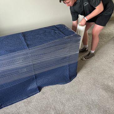 A mover wrapping a piece of furniture to protect it