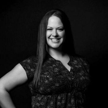 Smiling woman posing confidently against a dark background.
