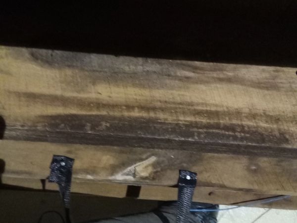 Black insulated duct secured with straps under a wooden beam.