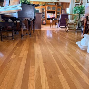 Cozy living room with piano and wooden flooring.