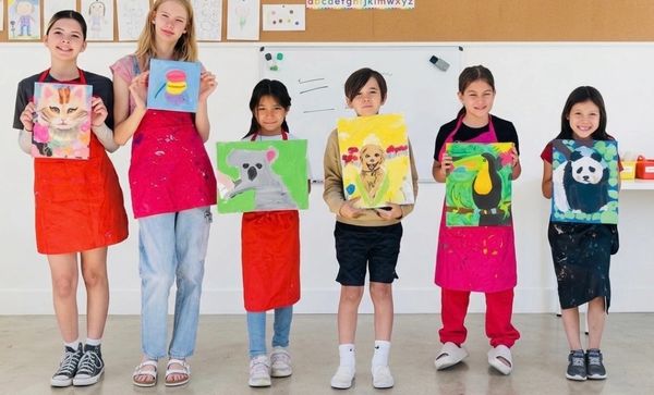 Children proudly holding animal paintings in an art class.