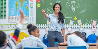 A smiling teacher calling on a student during science class.