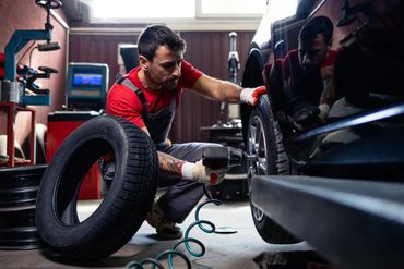 Mechanic changing a tire on a car in a workshop.