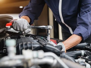 Mechanic using a wrench to repair a car engine.