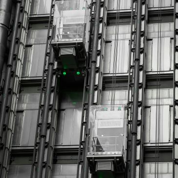 Two glass elevators moving up and down a modern building facade.