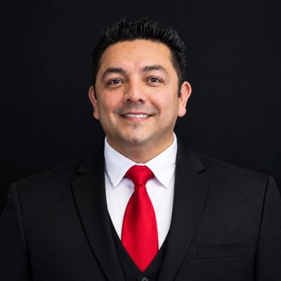 Smiling man in black suit with red tie.