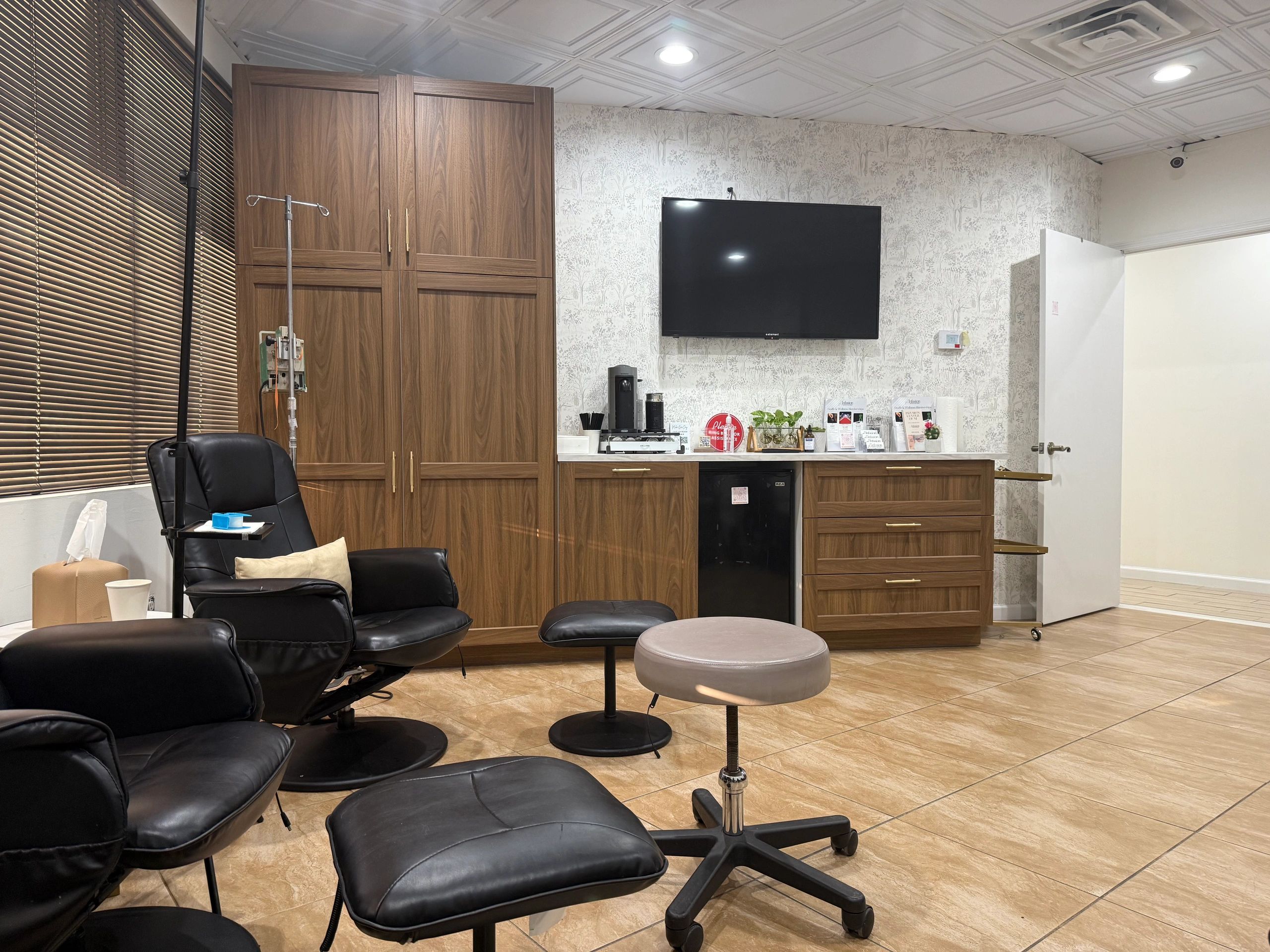 Cozy medical or spa room with black chairs and wood cabinets.