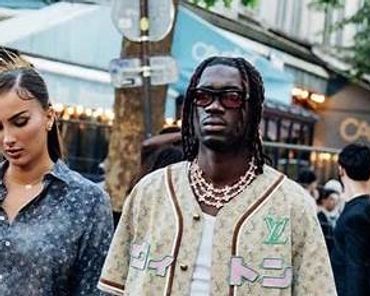 A stylish couple walking outdoors in designer outfits.