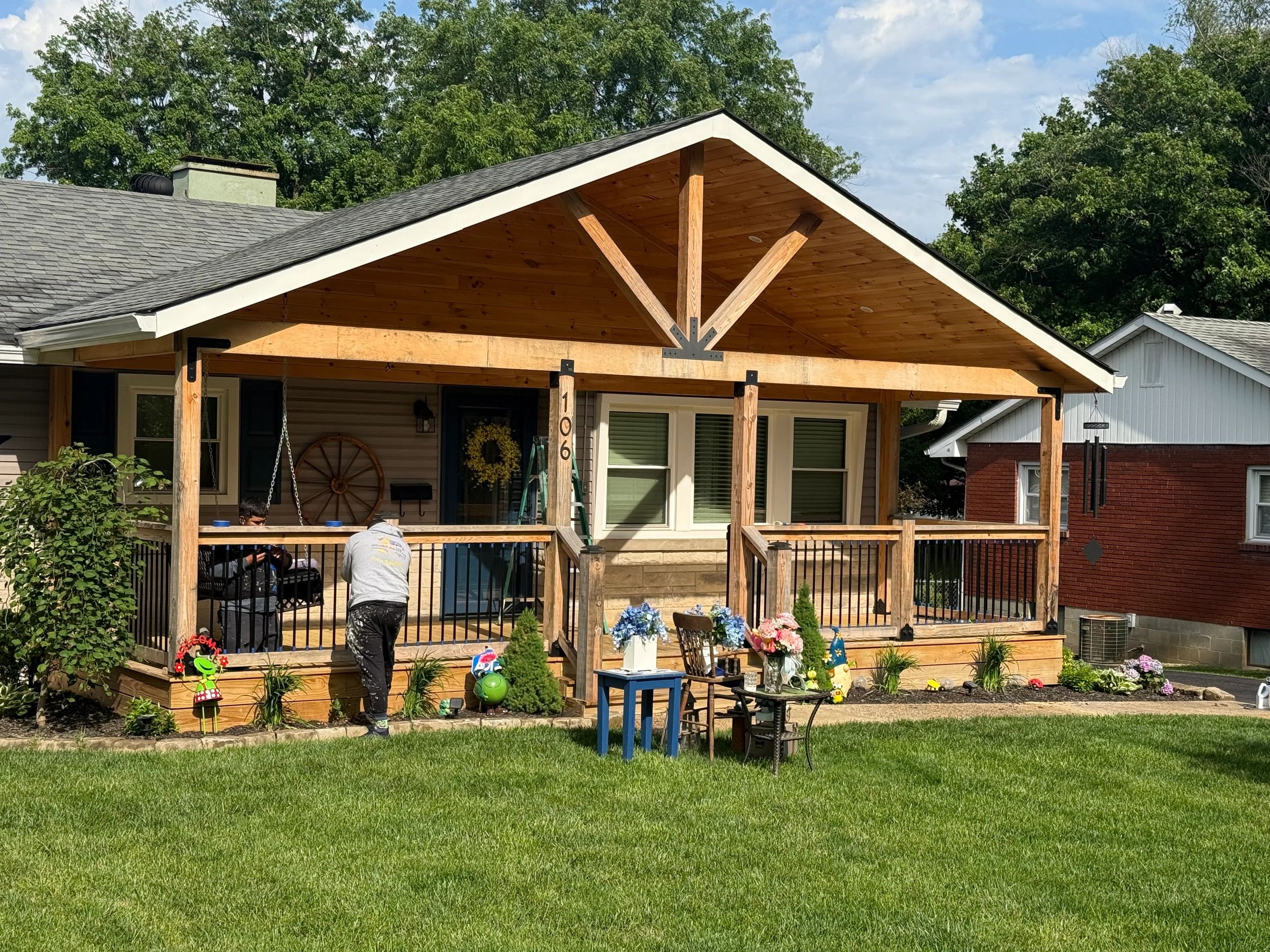 Cozy wooden porch with plants and outdoor seating on a sunny day.