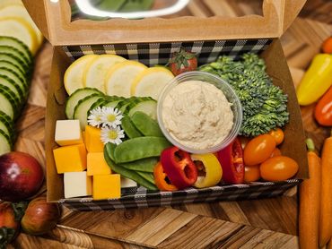 A colorful veggie box with hummus and cheese cubes.