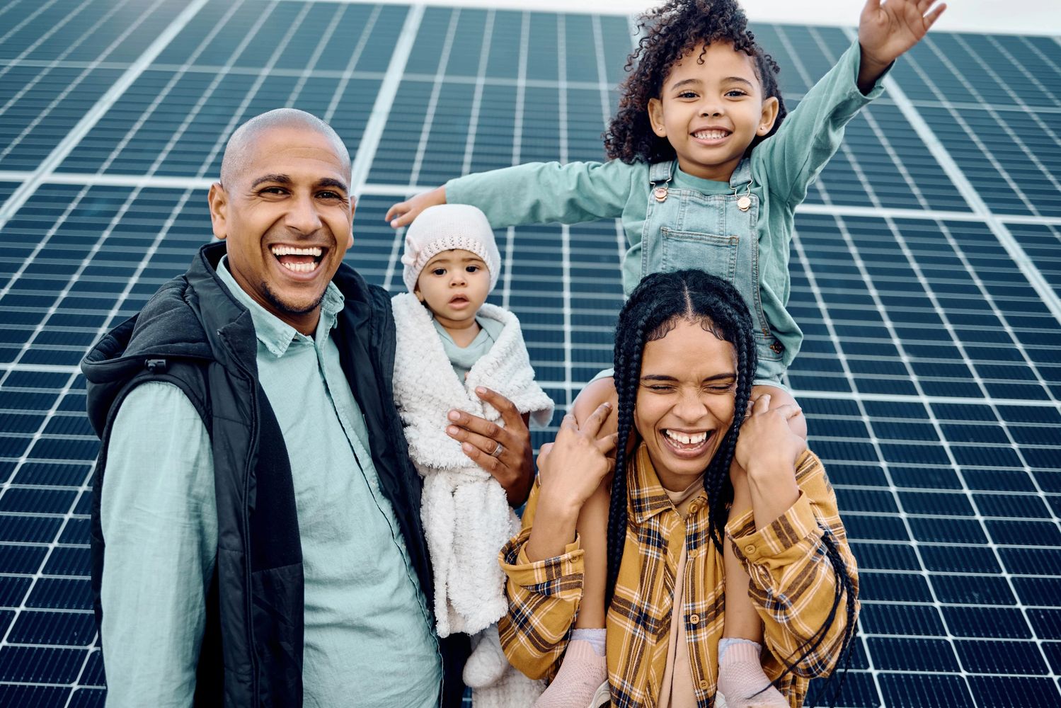 A smiling family in front of solar paneles