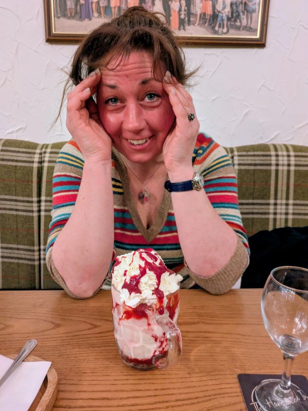 Woman smiling with a whipped cream and berry dessert in front of her.