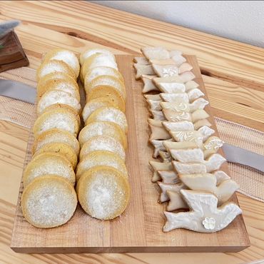 Group of sugar cookies on wooden board. One cookie circular, the other in a dove shape.