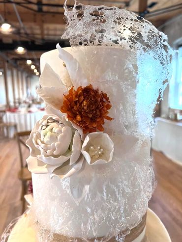 Edible flowers in white and burnt orange. Two Their white cake with sugar art.