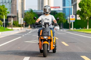 A young man is riding a three-wheeled cargo electric motorcycle