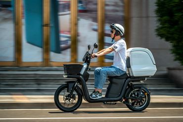 A man is riding a cargo electric scooter with a thermal cargo box