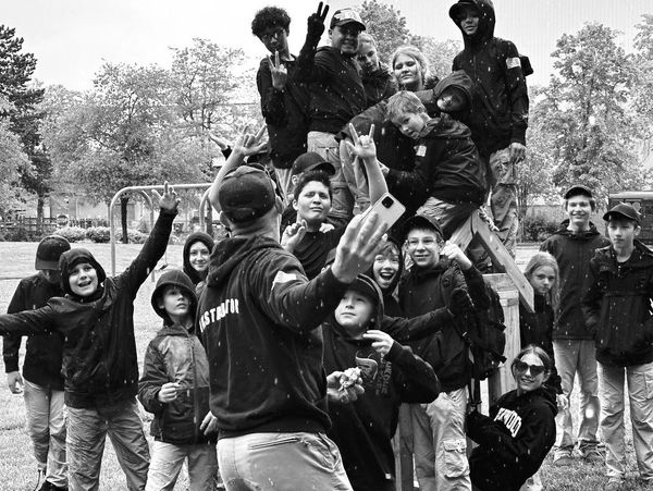 Group of young people posing for a selfie outdoors in the rain.
