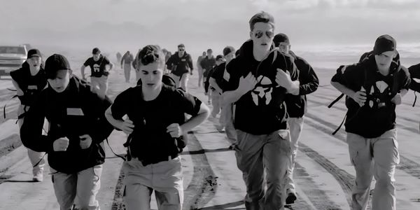 Group of young people running on a sandy terrain with backpacks.