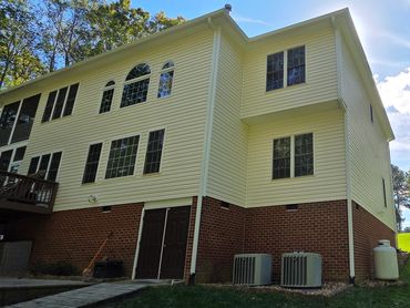 A large yellow and brick house with multiple windows and a grassy yard.