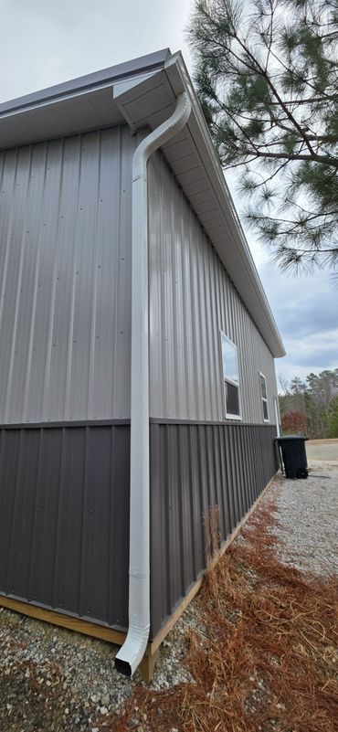 Metal building exterior with white gutter and downspout system.