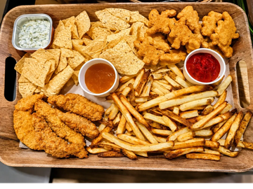 A wooden tray filled with fried chicken, French fries, nachos, and dipping sauces.