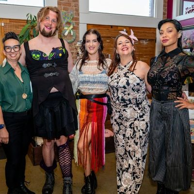 Five diverse people dressed in creative outfits, standing indoors and smiling at the camera.