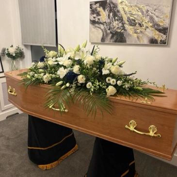 Coffin with white and blue flowers.