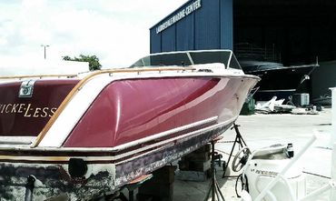 A red and white boat with 'TUSCANY' on the side on a boat lift.