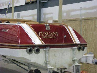 The back of a red boat with a 'TUSCANY' sticker on the side.