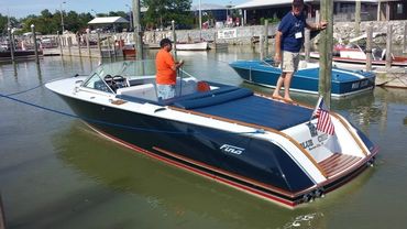 A blue and white boat with people on a trailer.