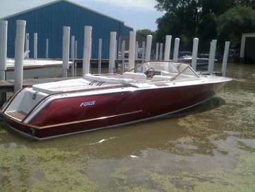 The side of a red boat at a dock.