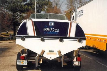 The back of a white boat on a trailer with blue and black stripes.