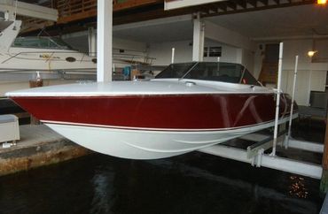 The back of a white and red boat on a lift inside a boathouse.