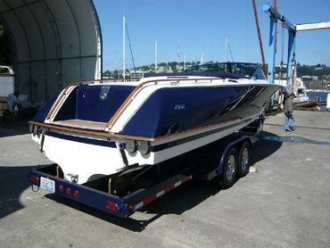 A blue and white boat on a trailer in a garage.