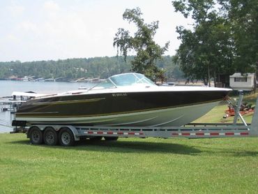 A large boat on a trailer on a grassy field.