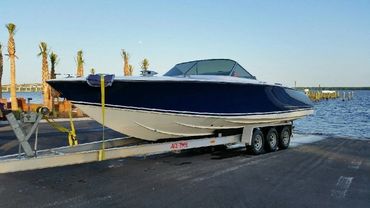 A blue boat with a white cover on a trailer.