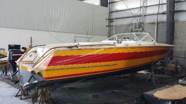 A yellow and orange boat on a trailer in a garage.