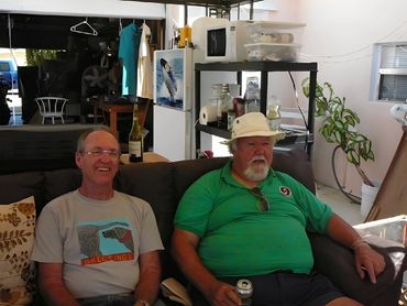 Two men sitting on a couch, posing for a photo.