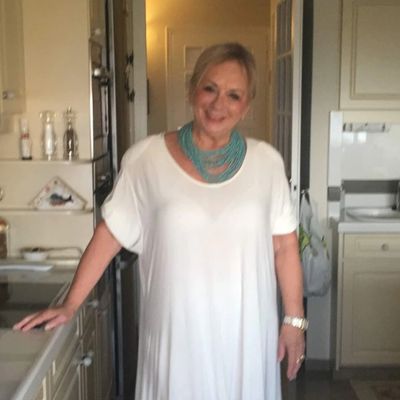 Woman in a white dress standing in a kitchen.