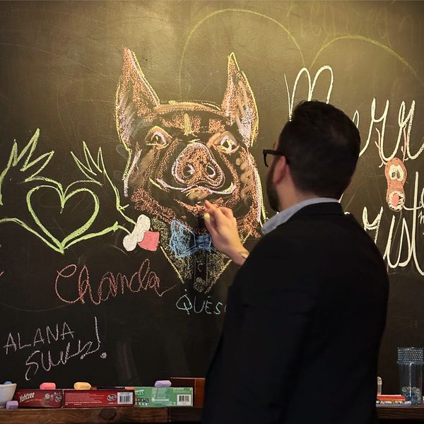 Guest drawing a pig on the chalkboard