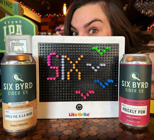 Bartender Gretchen displaying her design on the Lite Brite featuring Six Byrd Ciders
