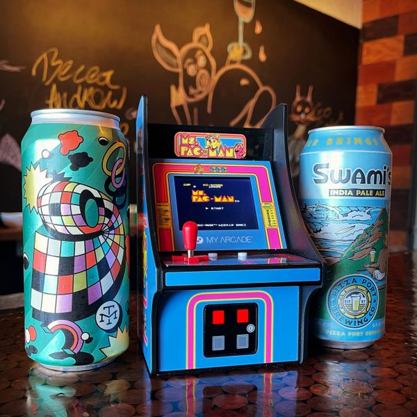 Miniature classic arcade game between two cans of beer