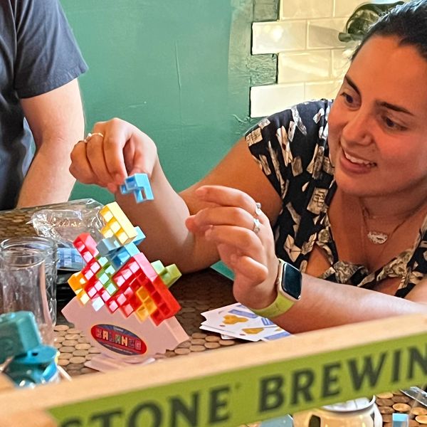 Guest playing a 3D Tetris-like game while enjoying a beer
