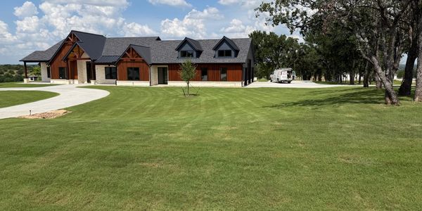 Modern house with a large green lawn and a curved driveway.
