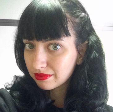 Owner of Key language Services, a woman with black hair and bangs, wearing red lipstick.