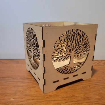 Wooden box with intricate tree cutout designs on each side.