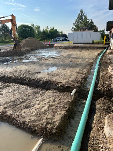 Excavation site with large green pipeline and construction machinery.