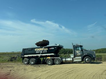 A dump truck with excavated dirt under clear sky.